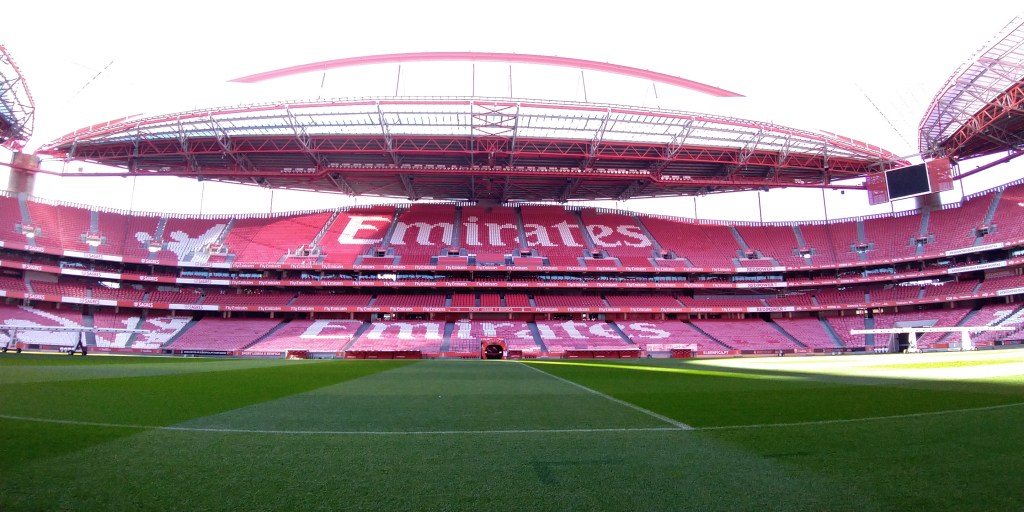 Una delle tribune dell'Estadio da Luz vista direttamente dal terreno di gioco, i seggiolini sono rossi mentre alcuni seggiolini bianchi compongono la scritta Emirates. Lo stadio si trova a Lisbona, Portogallo