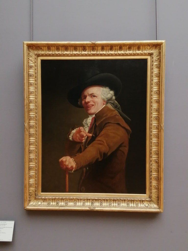 Autoritrato dell'autore che esprime un sorriso beffardo guardando negli occhi l'osservatore mentre lo indica, opera esposta al Louvre