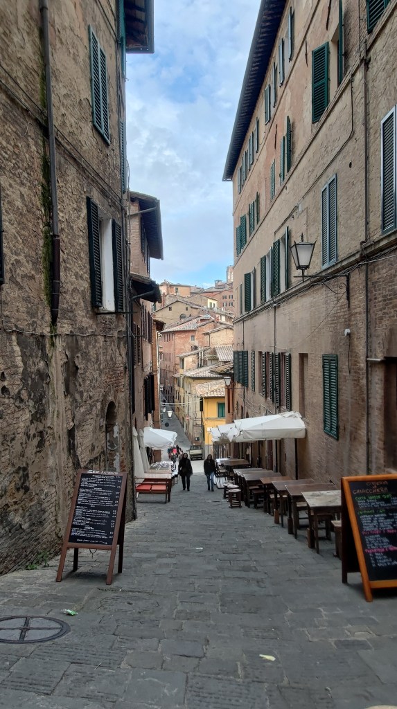 Vicoli medievali nel centro di Siena dove domina quel colore denominato proprio "terra di Siena, Siena, Toscana