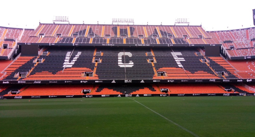 Estadio Mestalla, casa del Valencia, visto dal terreno di gioco verso le tribuna centrale con seggiolini arancioni e neri che formano un grande pipistrello