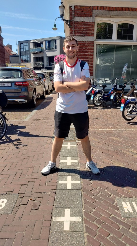 Matteo Albertazzi di Matteontheroad sul confine con un piede in Belgio e un'altro in Olanda, tra Baarle-Hertog e Baarle-Nassau, un luogo unico al mondo