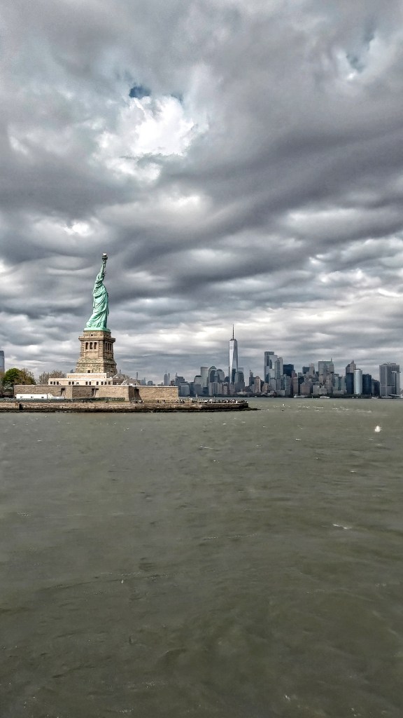La Statua della Libertà e dietro il profilo di Manhattan con i suoi grattacieli, New York, USA