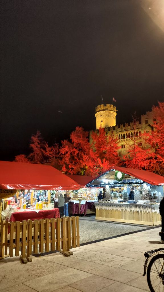 Il Castello del Buonconsiglio illuminato di sera e le casette dei mercatini di Natale, Trento