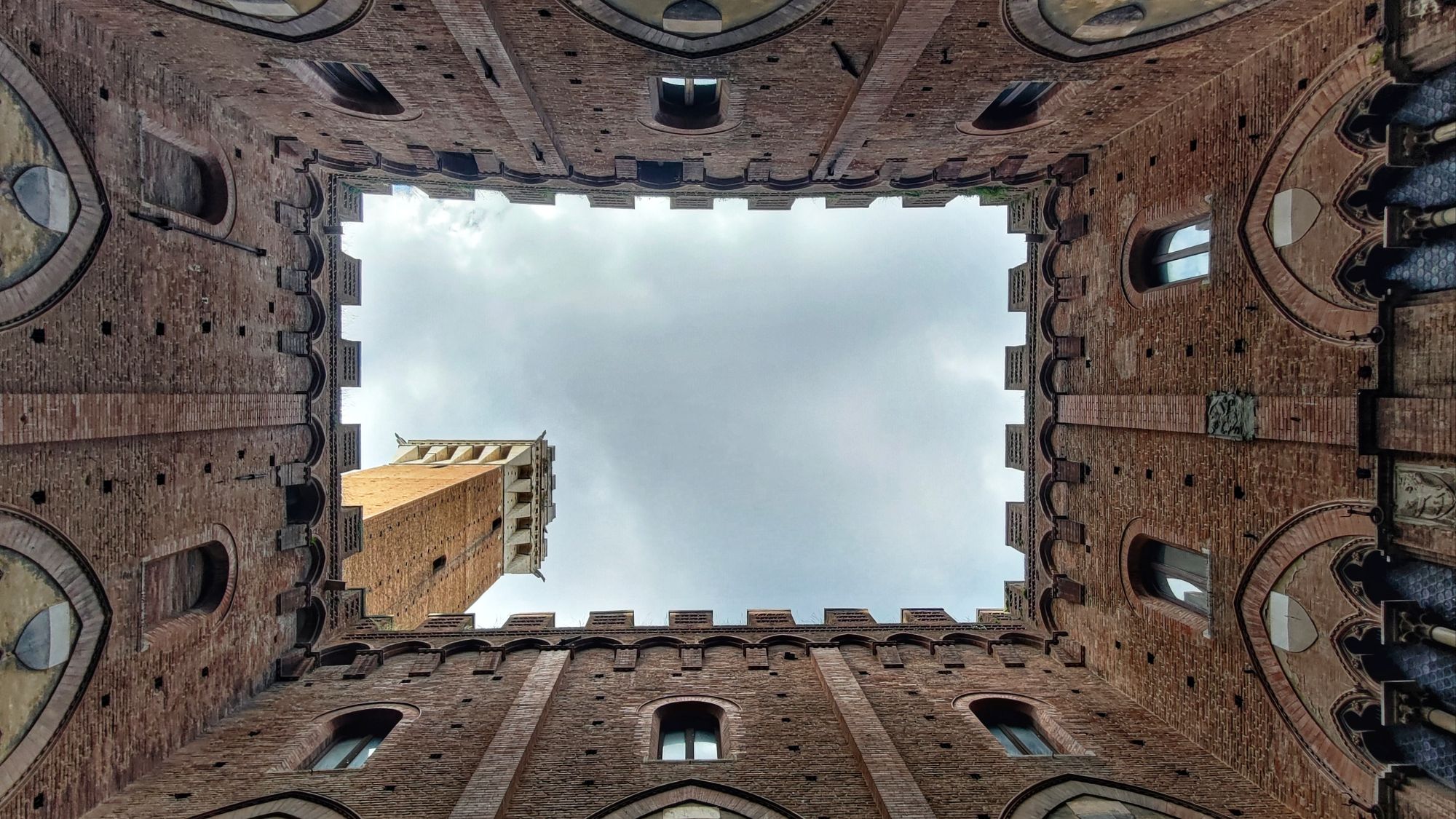 Vista verso l'alto dal cortile interno del Palazzo Pubblico di Siena che regala una prospettiva splendida sul cielo e la Torre del Mangia. Siena, Toscana